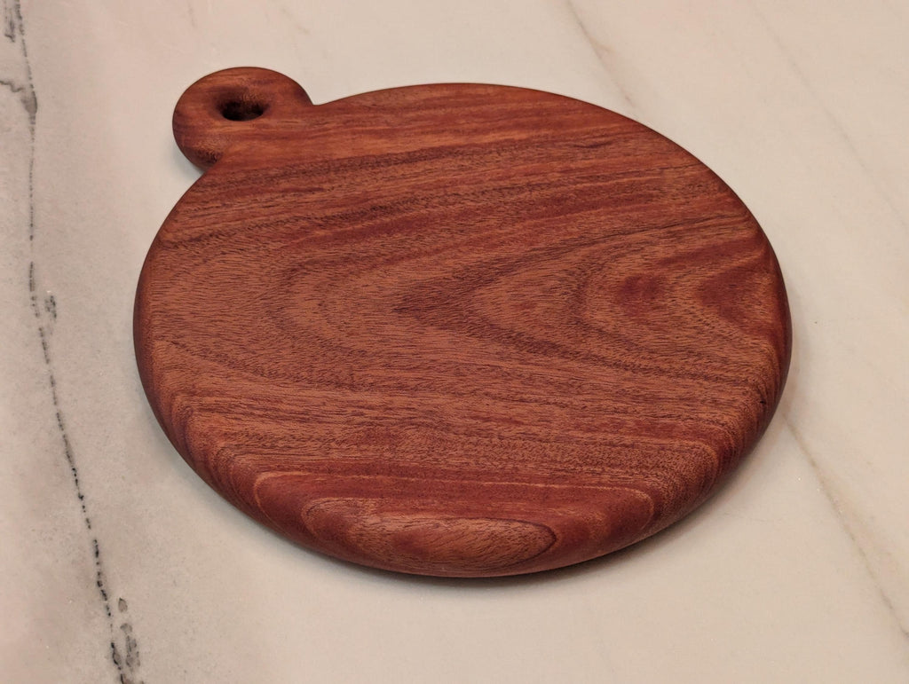 Round cherry cutting board with handle, angled view