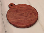 Round cherry cutting board with handle, angled view