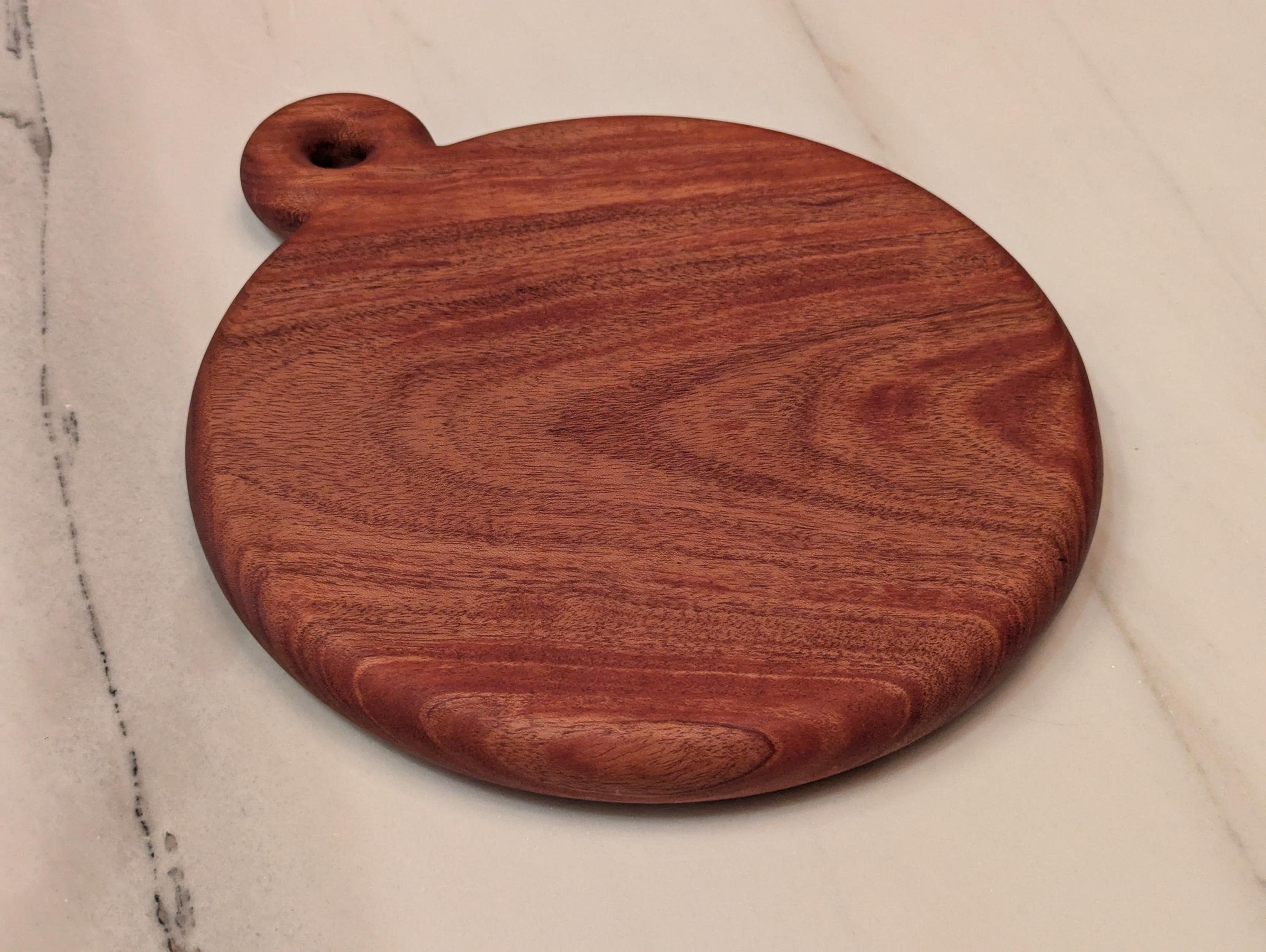 Round cherry cutting board with handle, angled view